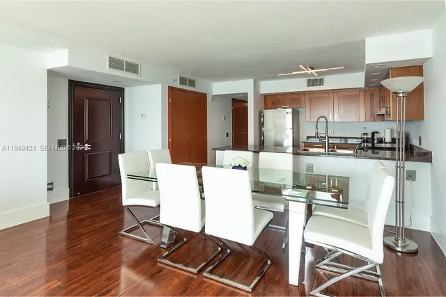 a living room with furniture a wooden floor and kitchen view