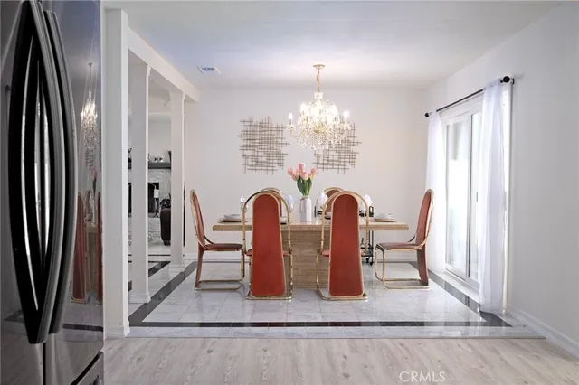 a kitchen with a refrigerator a stove a sink and a dining table with wooden floor