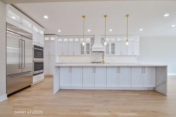 a large kitchen with stainless steel appliances kitchen island a large counter top and wooden floors