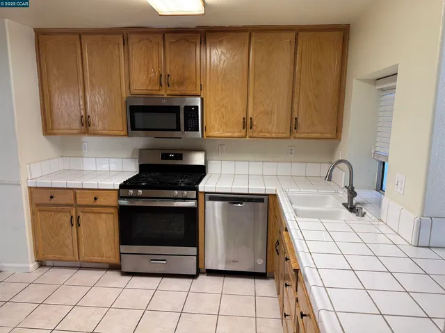 a kitchen with stainless steel appliances granite countertop a stove a sink and a microwave