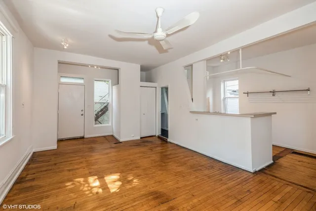 a view of a livingroom with wooden floor and a ceiling fan