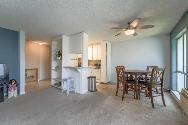 a living room with furniture a chandelier fan and a dining table
