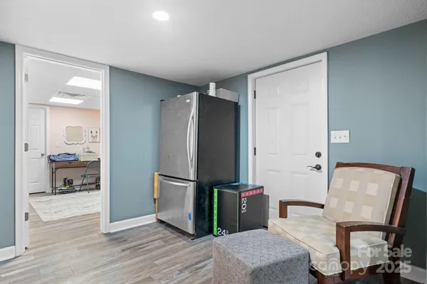 a view of a refrigerator in kitchen and an empty room with wooden floor