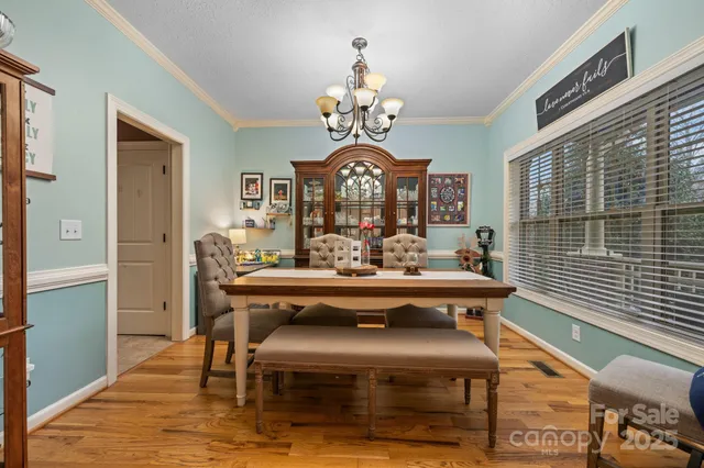 a view of a dining room with furniture a chandelier and wooden floor