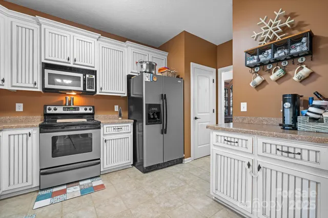a kitchen with stainless steel appliances white cabinets a stove a sink and a refrigerator