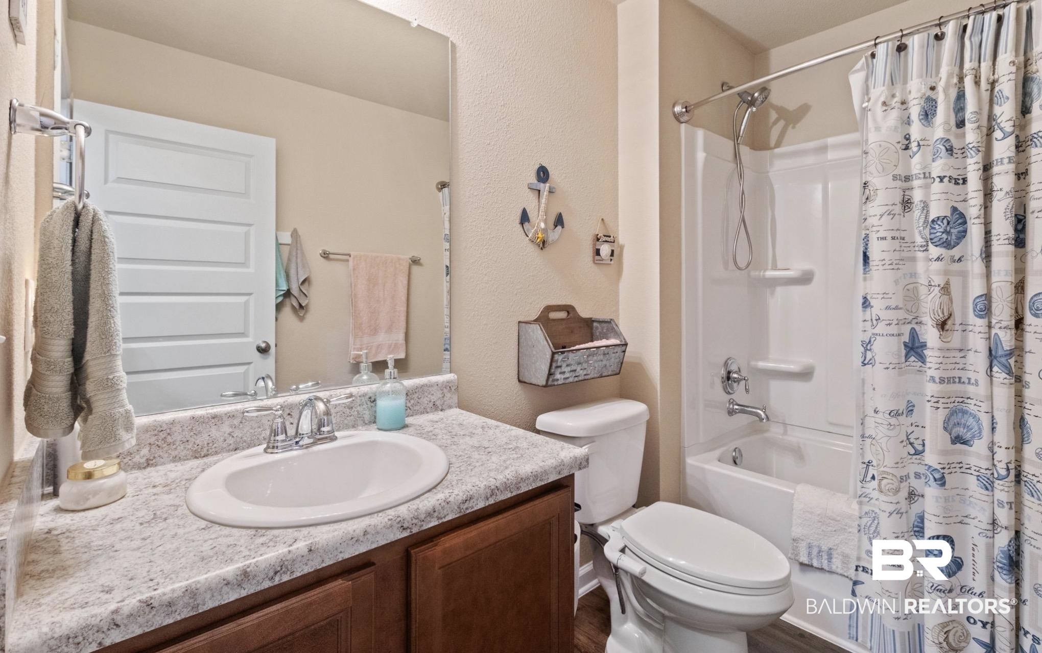 1676 Abbey Loop Foley, AL 36535 - Photo 19 of 31 Full bathroom featuring a vanity with a white oval sink, a speckled countertop, and wood-finish cabinetry