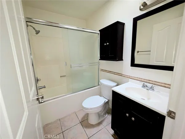 a view of a hallway with wooden floor and a bathroom