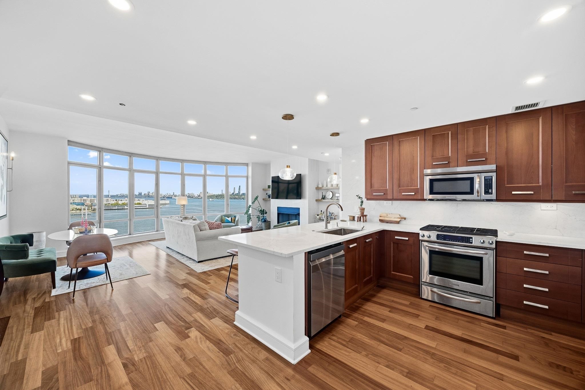 8100 River Road, Unit 1203 North Bergen, NJ 07047 - Photo 5 of 31 a open kitchen with stainless steel appliances granite countertop a stove top oven a refrigerator a sink and dishwasher with wooden floor