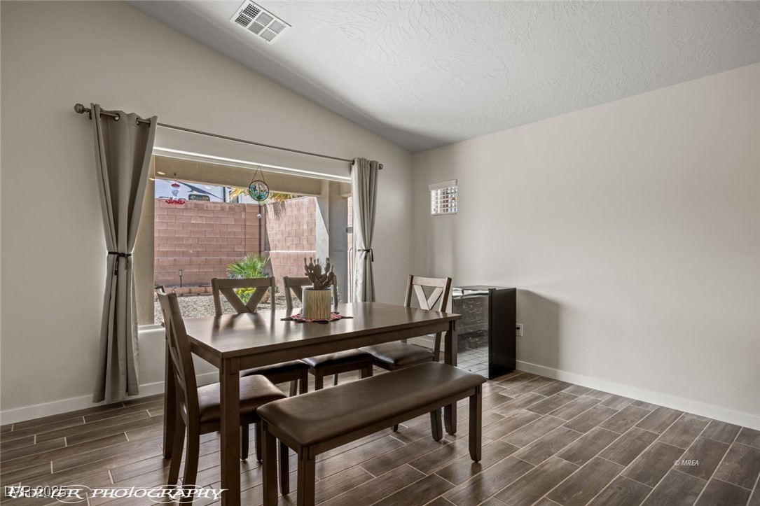 942 Shadow Hawk Ridge Mesquite, NV 89027 - Photo 24 of 67 Dining area featuring wood finish floors, vaulted ceiling, baseboards, plenty of natural light, and a textured ceiling
