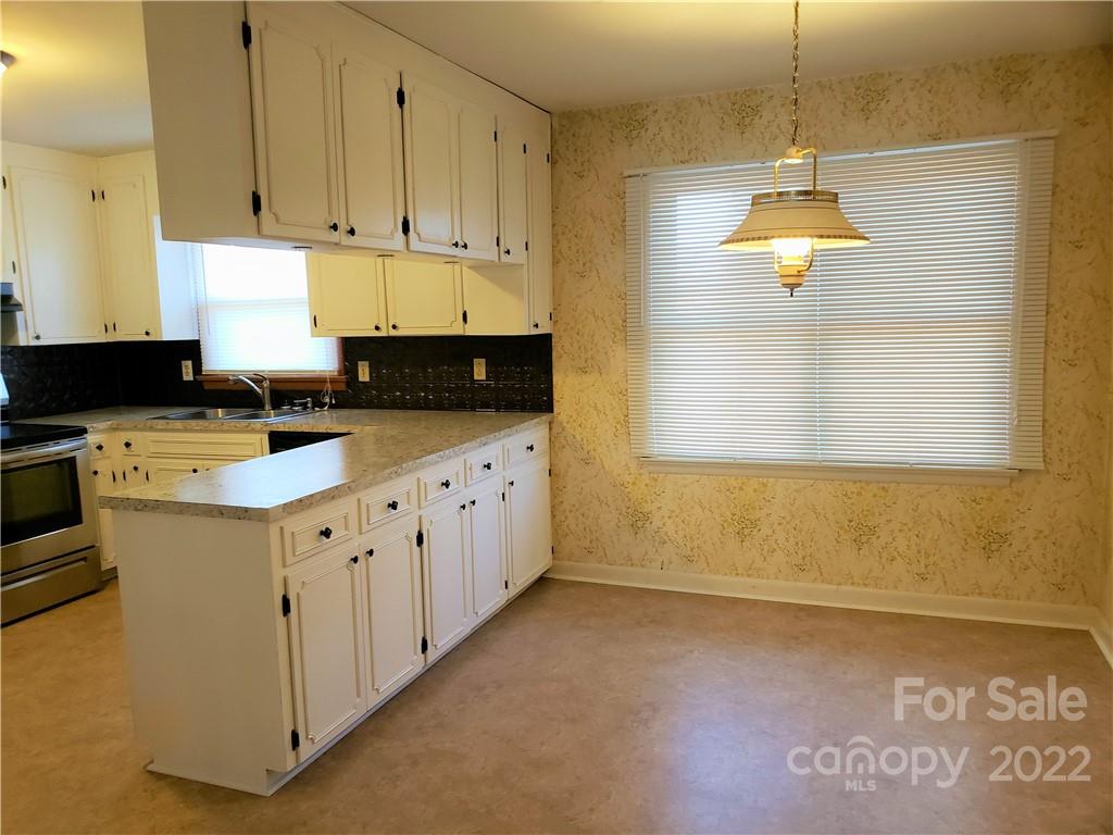 506 8th Street Southwest Conover, NC 28613 - Photo 7 of 38 a kitchen with granite countertop a sink a stove a counter space and cabinets