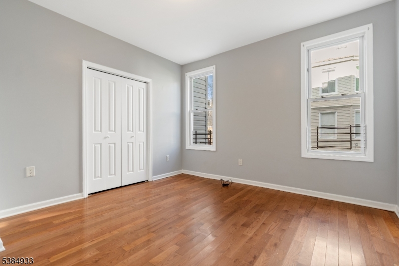 87 Columbia Avenue, Unit 3 Newark, NJ 07106 - Photo 4 of 9 an empty room with wooden floor and windows