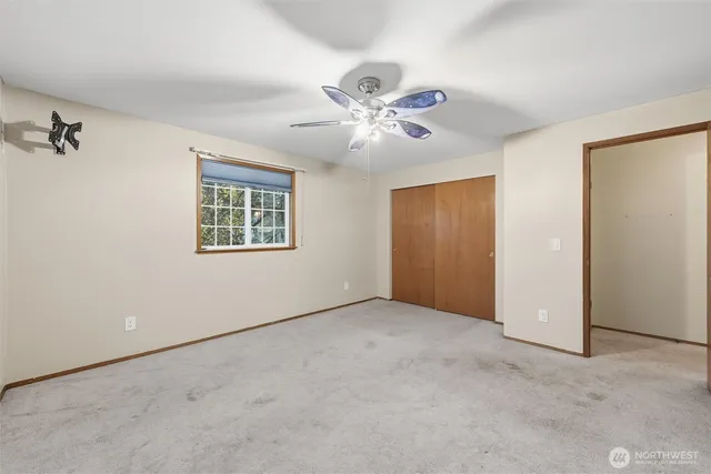 an empty room with windows and fan