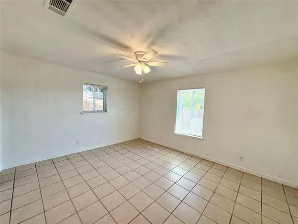 an empty room with windows and fan