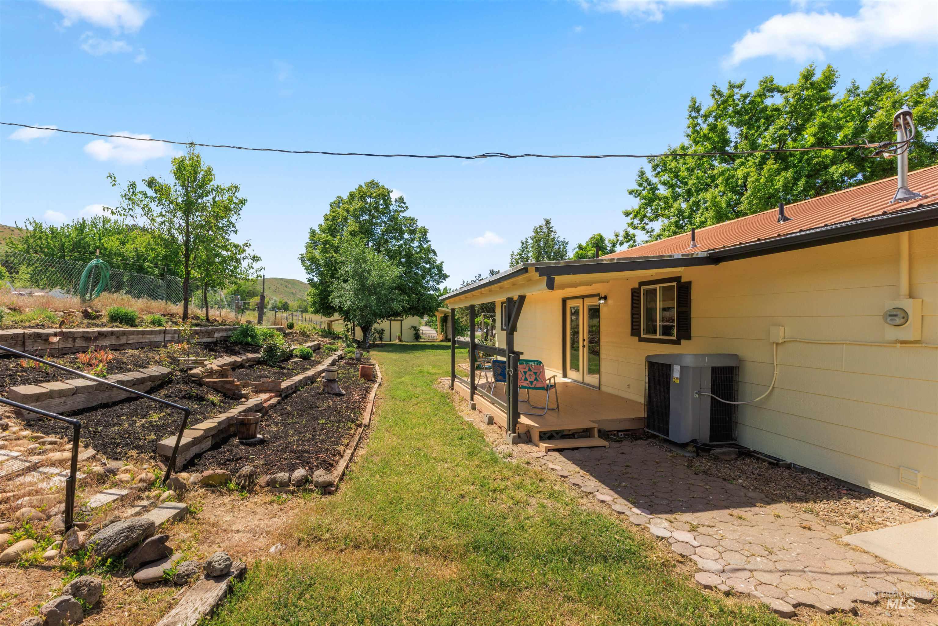 12184 Hill Road Payette, ID 83661 - Photo 32 of 35 Expansive backyard featuring a multi-tiered garden area with stone and timber retaining walls, a grassy lawn, and mature trees
