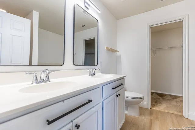 a bathroom with a granite countertop sink a toilet and a mirror