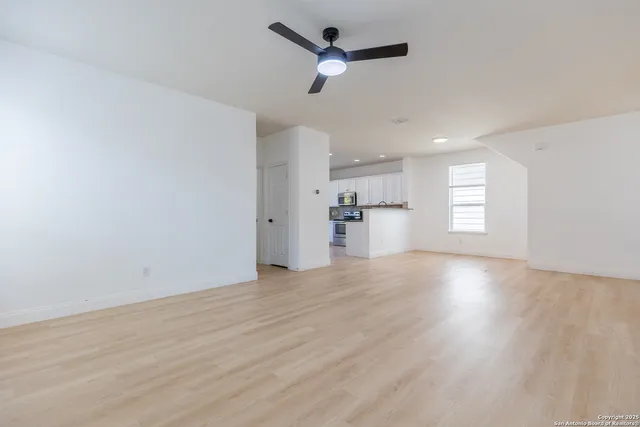 a view of empty room with wooden floor and ceiling fan