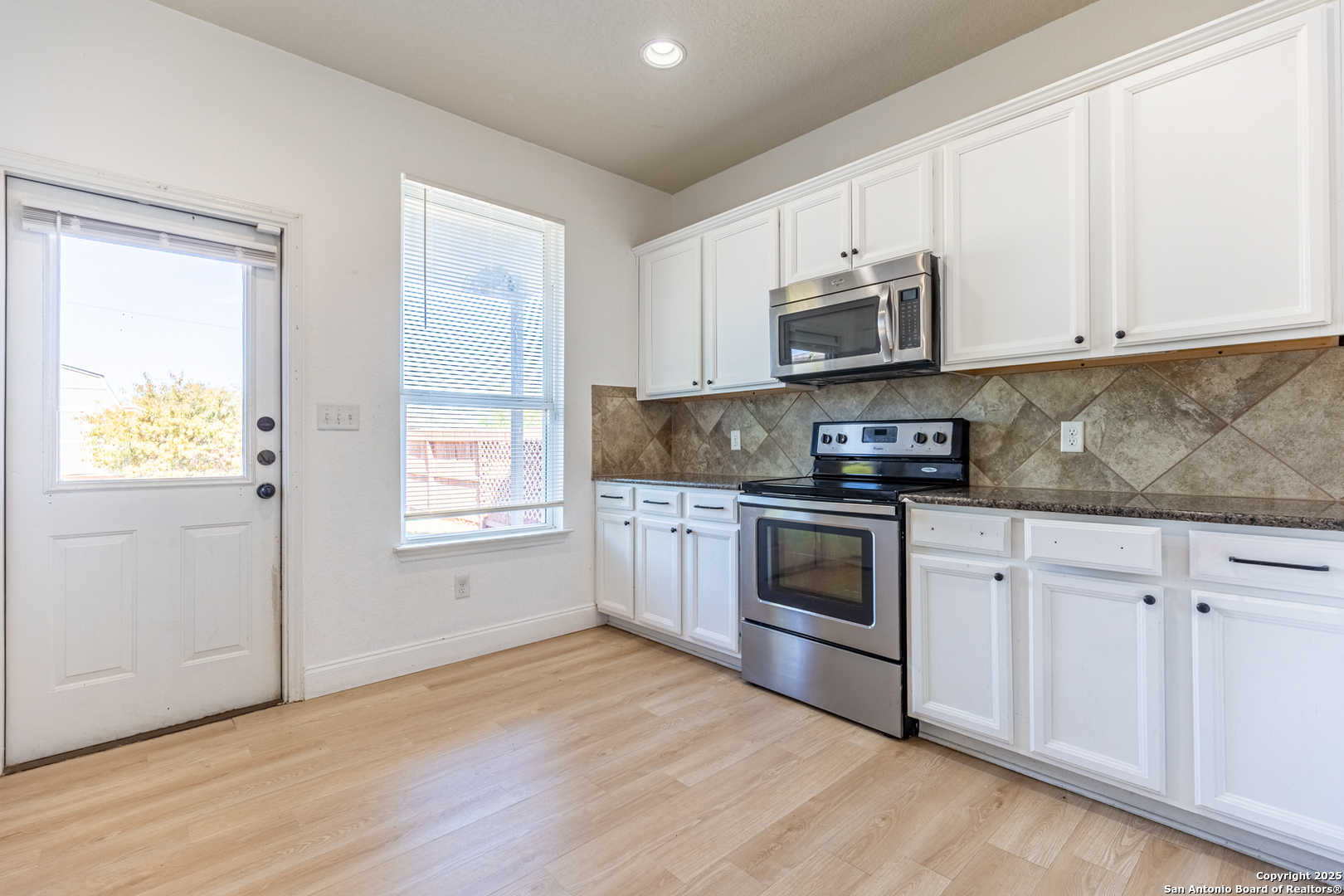 443 Harvest Point Selma, TX 78154 - Photo 8 of 33 a kitchen with granite countertop white cabinets and stainless steel appliances