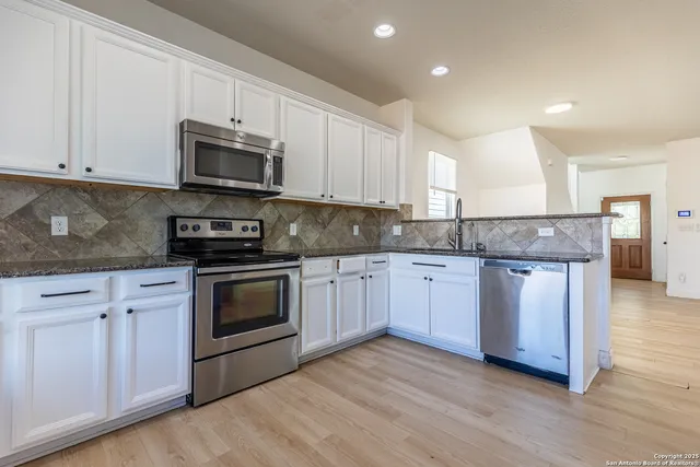 a kitchen with granite countertop a sink cabinets and stainless steel appliances