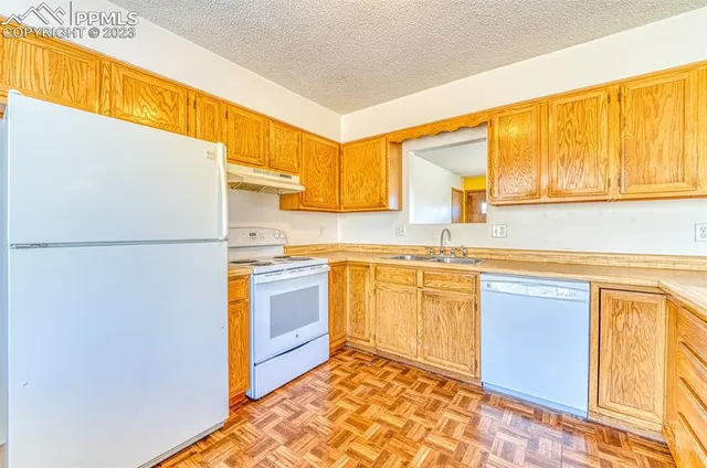 a kitchen with stainless steel appliances granite countertop a refrigerator a sink dishwasher a stove with white cabinets and wooden floor