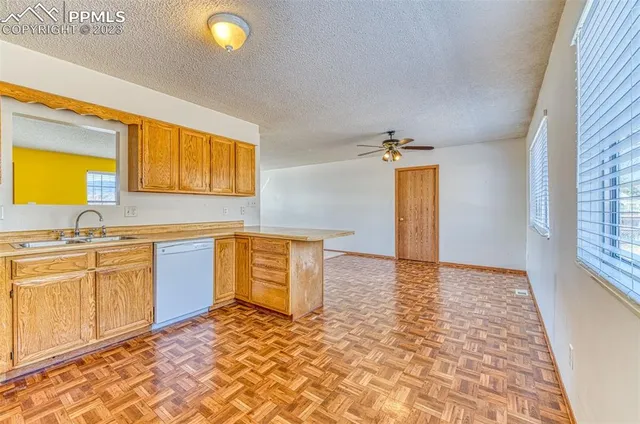 a view of a kitchen with a sink and dishwasher with wooden floor