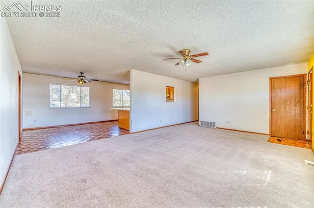 an empty room with windows and ceiling fan