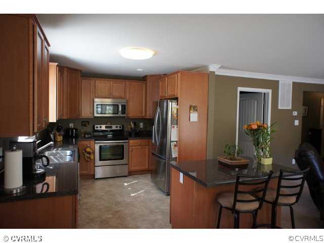 11605 Hillside Road Chester, VA 23831 - Photo 7 of 24 a kitchen with kitchen island a counter top space cabinets and stainless steel appliances