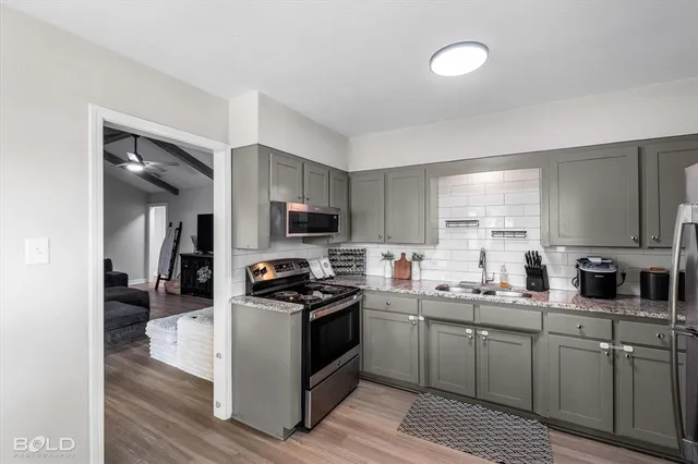 a kitchen with stainless steel appliances a sink a stove top oven a counter space and cabinets