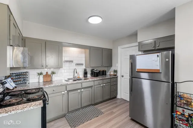 a kitchen with a refrigerator a stove a sink cabinets and a wooden floor