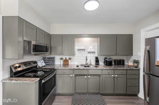 a kitchen with stainless steel appliances granite countertop a stove a sink dishwasher a refrigerator and a microwave