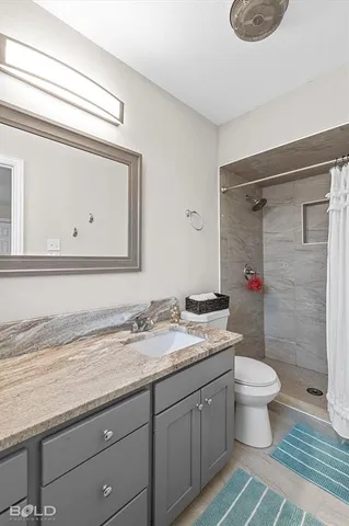 a bathroom with a granite countertop sink a toilet and a mirror