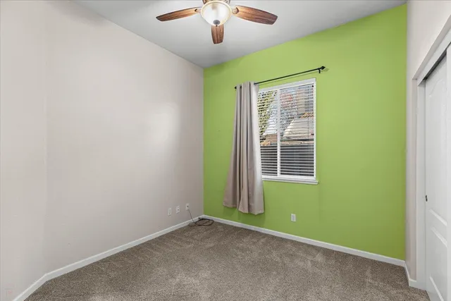 an empty room with a window and a ceiling fan