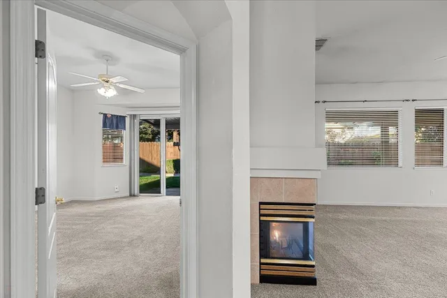 an empty room with chandelier fan and windows