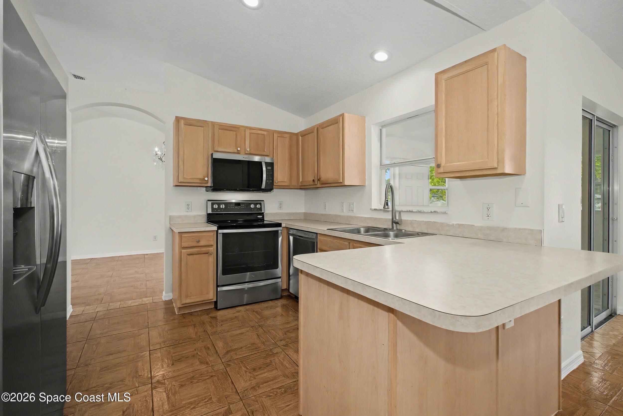 1175 Altamira Street Palm Bay, FL 32907 - Photo 13 of 37 a kitchen with stainless steel appliances a stove a sink a microwave and a refrigerator