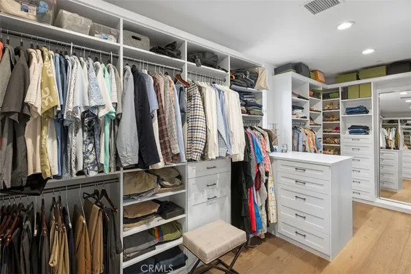 a view of walk in closet with clothes and shoes