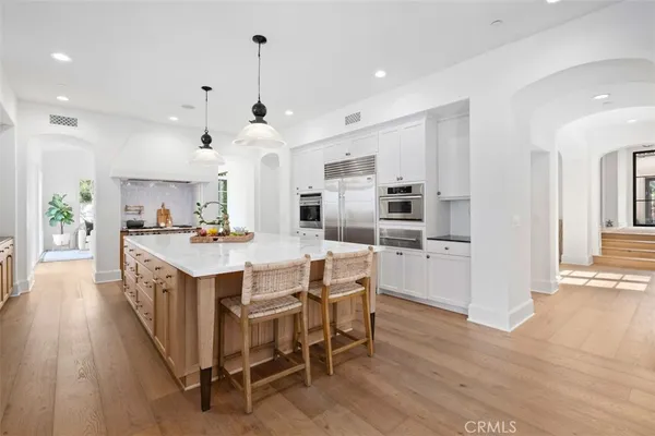 a kitchen with stainless steel appliances kitchen island granite countertop a wooden floor and white cabinets