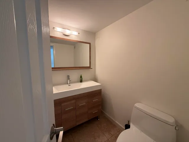 a bathroom with a toilet sink vanity and mirror