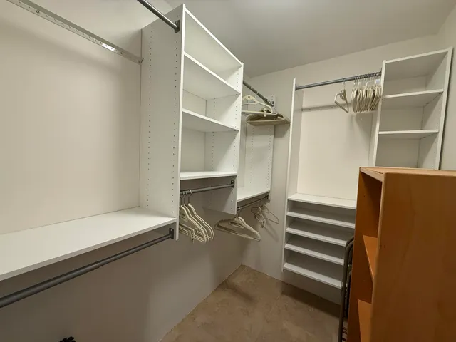 a view of walk in closet with empty racks