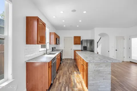 a large kitchen with stainless steel appliances granite countertop a sink and wooden cabinets