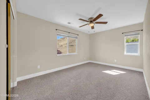 an empty room with windows and ceiling fan