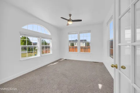 an empty room with windows and ceiling fan