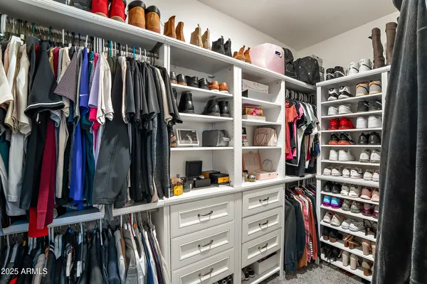 a view of walk in closet with clothes and shoes