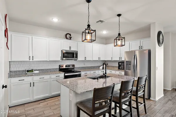 a kitchen with stainless steel appliances kitchen island granite countertop a sink a stove a refrigerator and cabinets