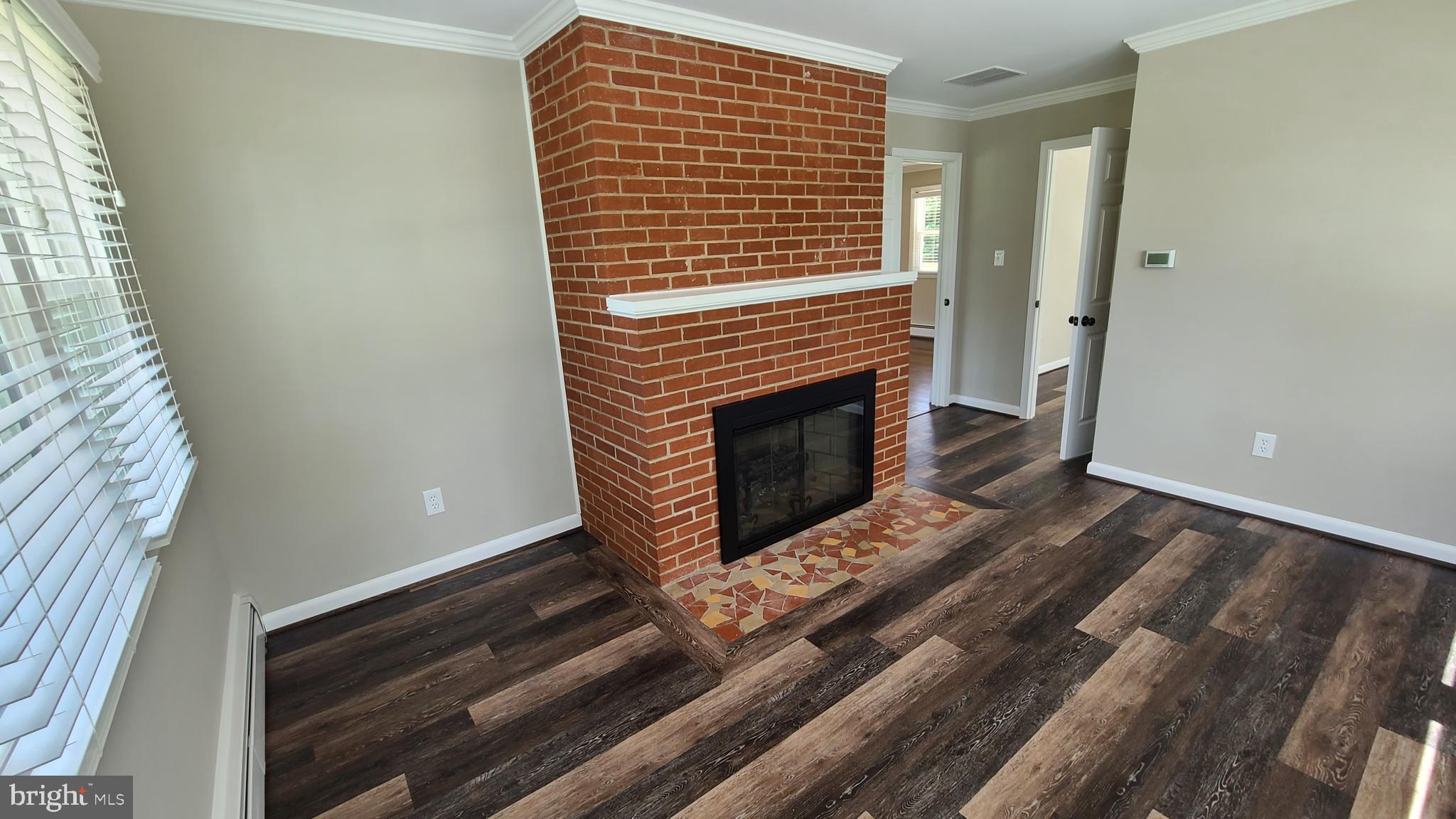 7 Cedar Drive Sterling, VA 20164 - Photo 4 of 40 a view of an empty room with wooden floor a fireplace and a window