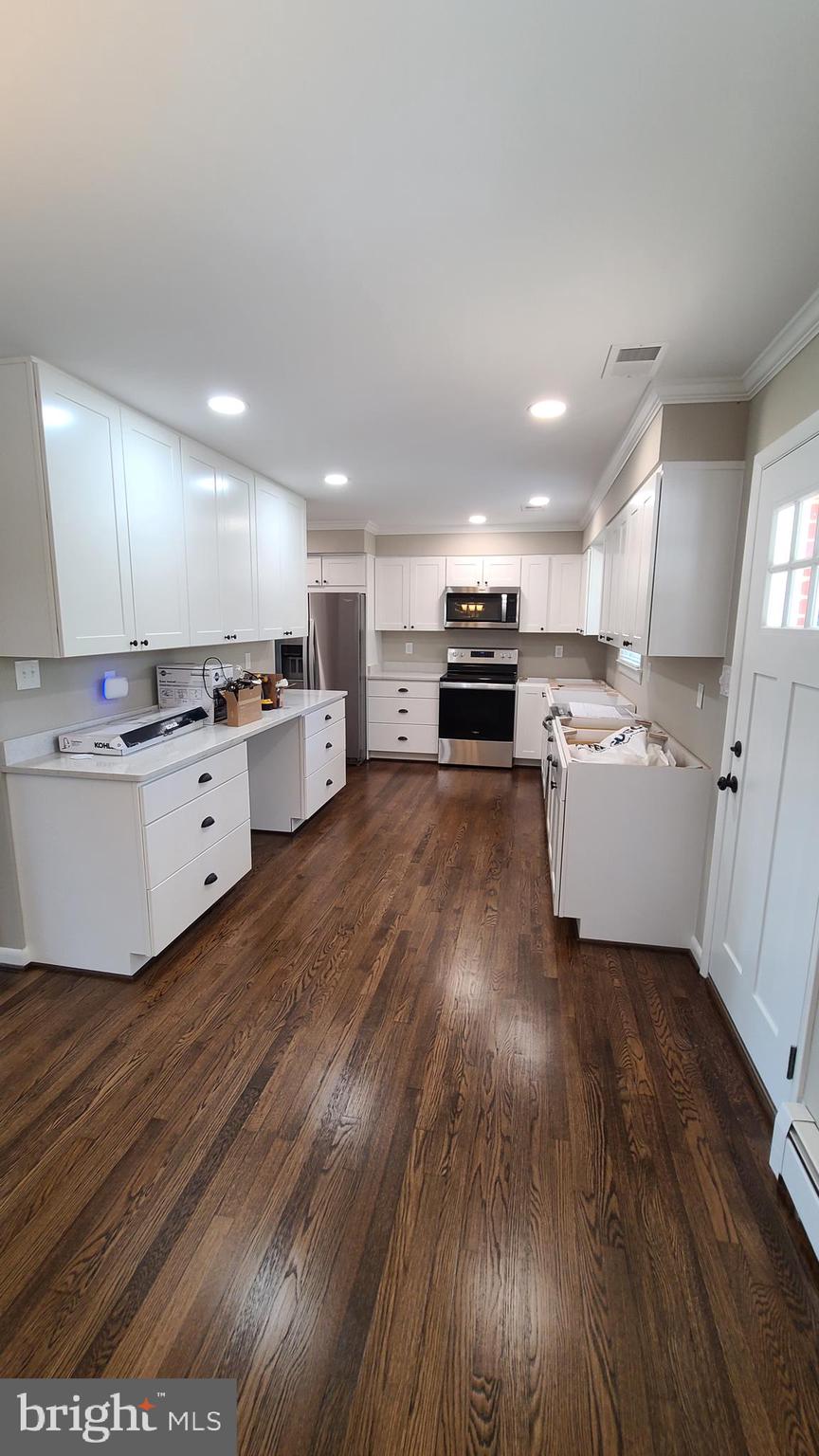 7 Cedar Drive Sterling, VA 20164 - Photo 6 of 40 a kitchen with a sink dishwasher stove and white cabinets with wooden floor