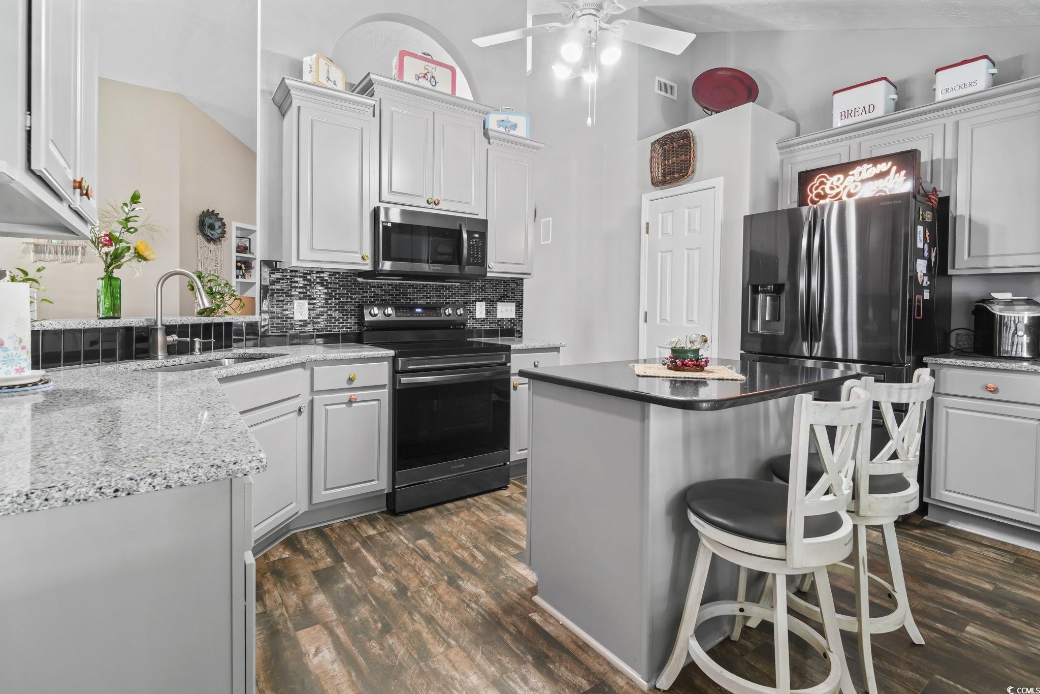 4105 Eva Bay Drive Murrells Inlet, SC 29576 - Photo 4 of 40 Kitchen featuring stainless steel appliances, a breakfast bar area, dark wood finished floors, backsplash, and high vaulted ceiling