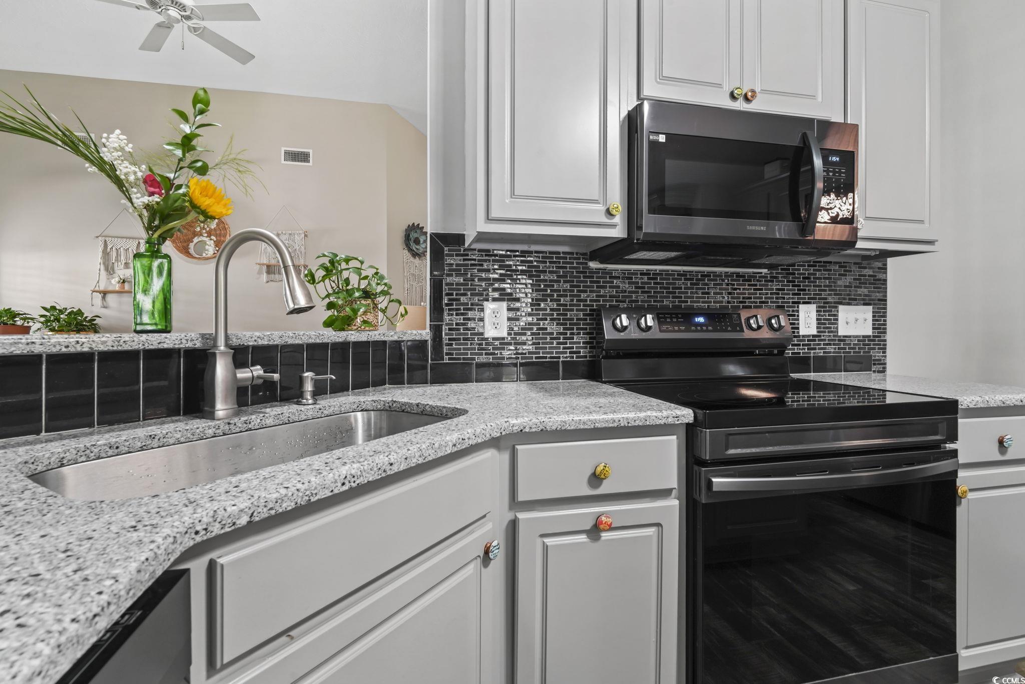 4105 Eva Bay Drive Murrells Inlet, SC 29576 - Photo 6 of 40 Kitchen featuring black electric range, stainless steel microwave, tasteful backsplash, and light stone countertops