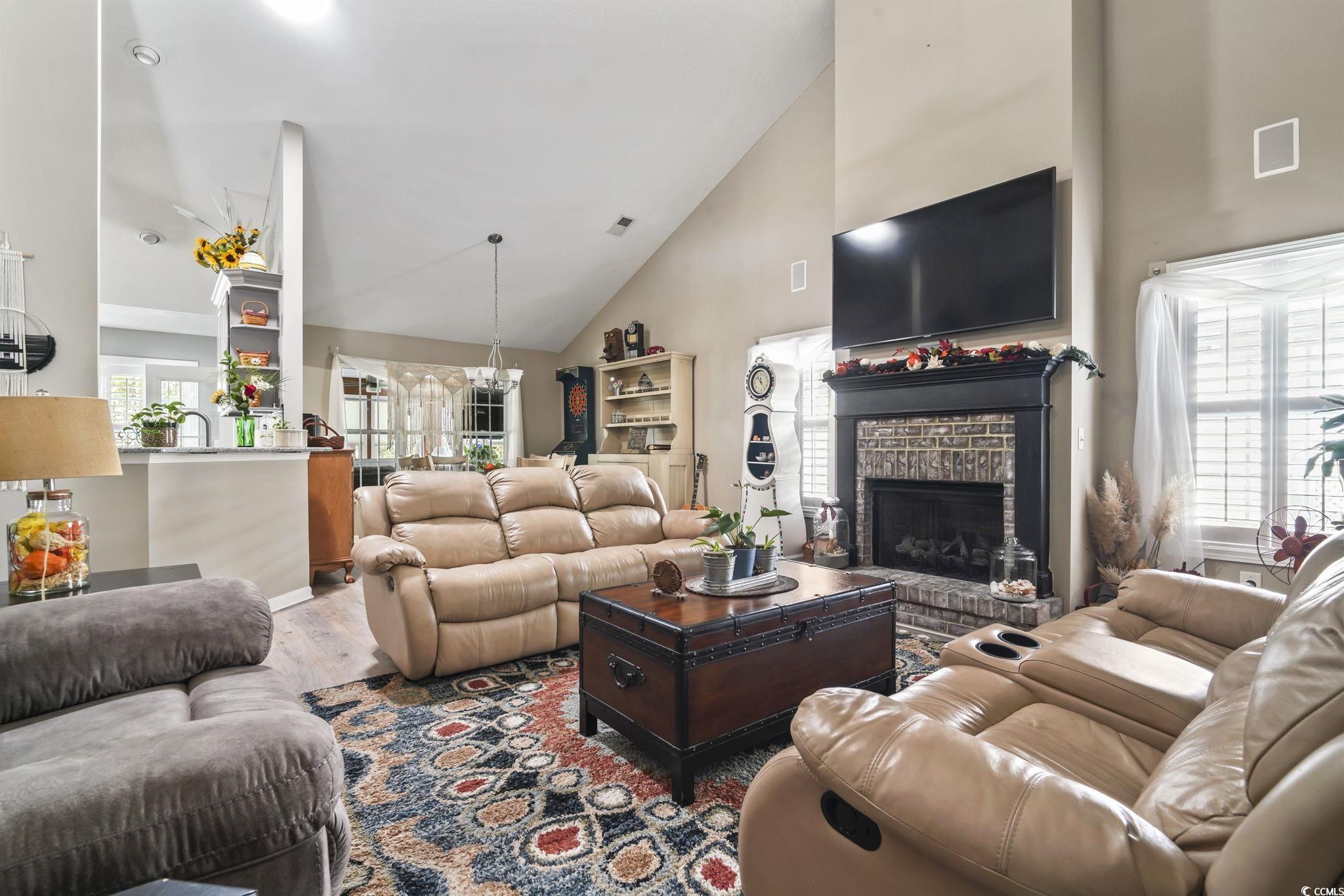 4105 Eva Bay Drive Murrells Inlet, SC 29576 - Photo 8 of 40 Living room with high vaulted ceiling, wood finished floors, a fireplace, and a chandelier