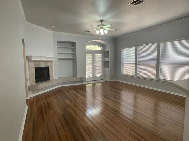 a view of an empty room with wooden floor fireplace and a window