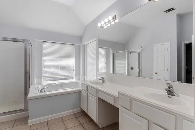 a bathroom with a sink a large mirror and a bathtub next to a window