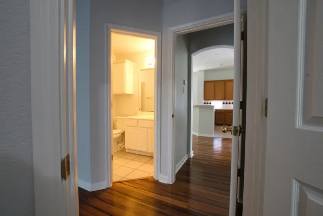 a view of a hallway with wooden floor and a room